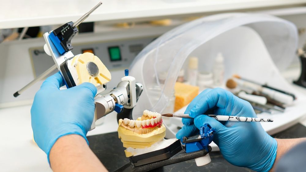 Dental prosthesis work. Denture work. Teeth painting. Dental technician working with tooth denture at prosthesis laboratory.