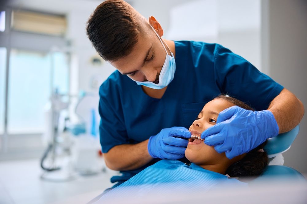 Young stomatologist examining teeth of African American girl during appointment